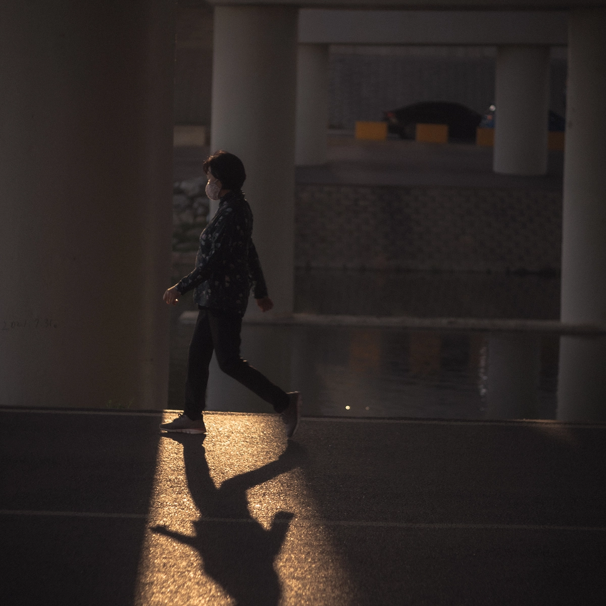 Solitary figure walking in sunlit corridor